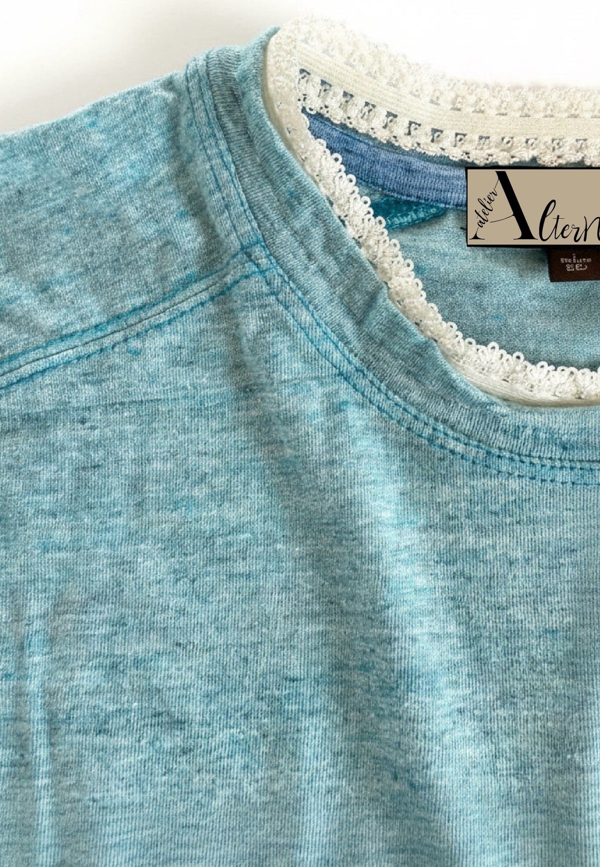 Close-up of a light blue heathered knit top with a white lace-trimmed collar.